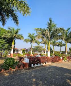 a row of palm trees and bushes in a park at Girvana Resorts in Sāsan Gīr