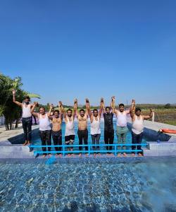 a group of men standing next to a swimming pool at Girvana Resorts in Sāsan Gīr