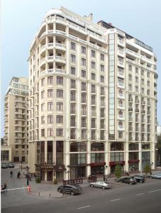 un grand bâtiment blanc avec des voitures garées devant lui dans l'établissement City Center Apartment, à Odessa