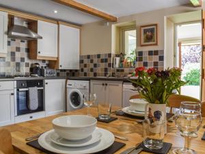 a kitchen with a wooden table with plates and wine glasses at Acorn Cottage in Ashover