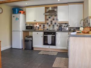 a kitchen with white appliances and white cabinets at Acorn Cottage in Ashover