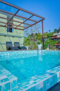 a swimming pool with two chairs and a pergola at Mistara Ella in Ella