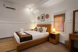 a bedroom with a large bed and a window at Puri Anyar Ubud by Puri Signatures in Ubud