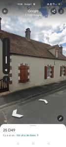 a white building with brown shuttered windows on a street at Linstant tranquille in Romorantin