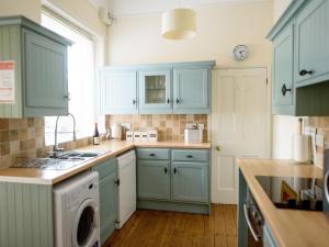 a kitchen with blue cabinets and a washing machine at Langetot in Bury Saint Edmunds