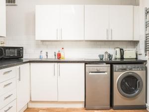 a kitchen with white cabinets and a dishwasher at Newport House Lower in Newport