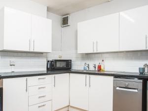 a white kitchen with white cabinets and a microwave at Newport House Lower in Newport