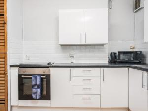 a white kitchen with white cabinets and a microwave at Newport House Lower in Newport