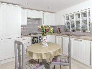 a kitchen with a table with a vase of flowers on it at Firlands Lodge - Ukc6205 in Nairn