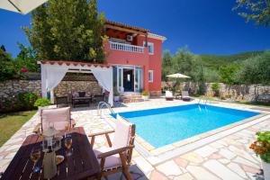 a villa with a swimming pool in front of a house at Villa Marina Epavlis by Villa Plus in Karavomylos