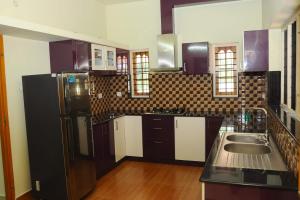 a kitchen with a black refrigerator and a sink at SHANKARAM Homestay in Kodanad