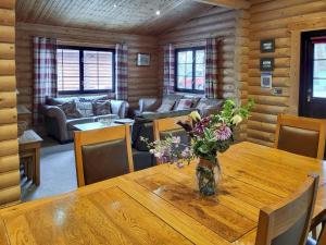 a room with a wooden table with a vase of flowers on it at Tyne Log Cabin - Uk3480 in West Thirston