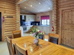 a kitchen with a wooden table with a vase of flowers on it at Tyne Log Cabin - Uk3480 in West Thirston