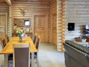 a dining room with a wooden table and a couch at Tyne Log Cabin - Uk3480 in West Thirston