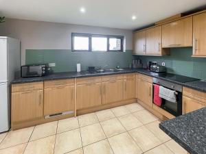 a kitchen with wooden cabinets and a sink and a refrigerator at Cherry Pip in Uckfield