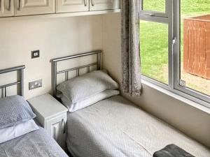 a bedroom with two beds next to a window at Aspen Lodge - Uk51190 in Morpeth +3 photos