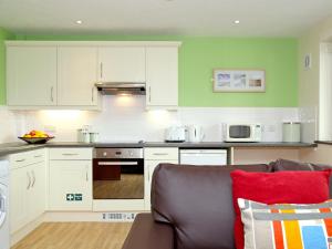 a kitchen with white cabinets and a couch at Birch Cottage in Uckfield