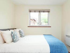 a bedroom with a white bed with a window at Birch Cottage in Uckfield