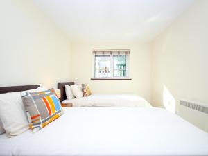 a white bedroom with two beds and a window at Birch Cottage in Uckfield