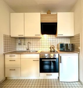 a kitchen with white cabinets and a sink and a refrigerator at Ferienappartement Dümmerling in Lembruch in Lembruch