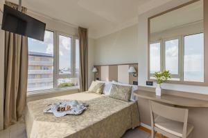 a hotel room with a bed and a desk and windows at Hotel Cristallo in Riccione