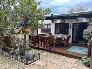 a wooden deck with a table and chairs on it at Twilight Cottage in Plettenberg Bay