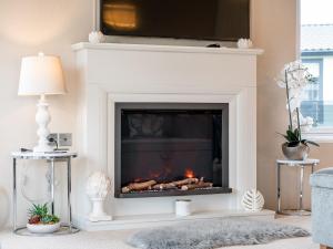 a living room with a fireplace with a tv above it at Lyndale 18 in St. Andrews +22 photos
