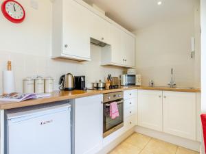 a kitchen with white cabinets and a clock on the wall at Hop Cottage - Ukc6134 in Eastdean