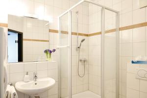 a white bathroom with a shower and a sink at Vinotel Dirmstein in Dirmstein