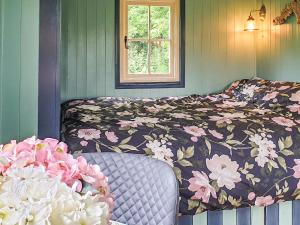 a bedroom with a bed with a flowered blanket and a window at Dorset Alpaca Shepherd's Hut in Dorchester