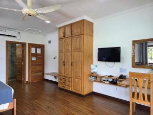a living room with a television and a wooden cabinet at Drake Seaside Studio Apartments in Bel Ombre