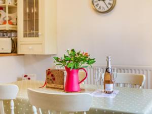 a table with a bottle of wine and a vase with flowers at Peaseblossom House in Alnwick