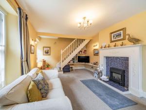 a living room with a white couch and a fireplace at Peaseblossom House in Alnwick