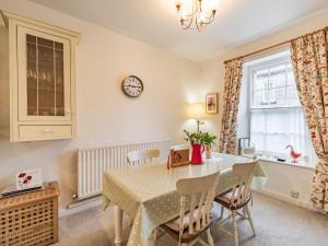 a dining room with a table and chairs and a clock on the wall at Peaseblossom House in Alnwick