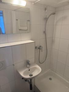 a white bathroom with a sink and a shower at Studio James in Hombrechtikon
