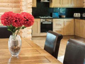 a vase of red flowers sitting on a wooden table at Hadrians Lodge - Uk3478 in West Thirston