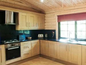 a kitchen with wooden cabinets and black counter tops at Hadrians Lodge - Uk3478 in West Thirston