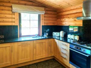 a kitchen with wooden cabinets and a stove at Hadrians Lodge - Uk3478 in West Thirston +5 photos