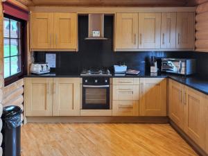 a kitchen with wooden cabinets and a stove top oven at Tweed Log Cabin-Uk3479 in West Thirston