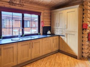a kitchen with wooden cabinets and a sink and a window at Tweed Log Cabin-Uk3479 in West Thirston