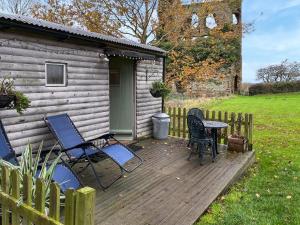 a deck with chairs and a table and a house at The Shepherds Hut - Uk50986 in Sheriff Hutton