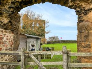 an arch in a stone building with a fence and a field at The Shepherds Hut - Uk50986 in Sheriff Hutton