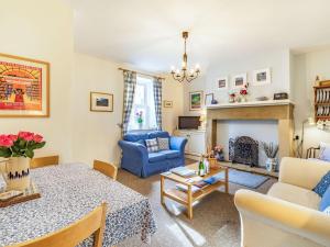 a living room with a table and a blue couch at Juliet Cottage in Alnwick