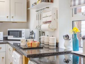 a kitchen with white cabinets and a counter top at Juliet Cottage in Alnwick