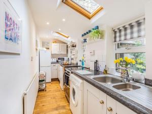 a kitchen with white cabinets and a sink and a window at Juliet Cottage in Alnwick