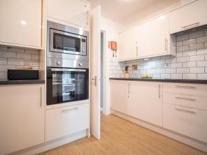 a kitchen with white cabinets and a microwave at Dalmore-Ukc5067 in Aviemore
