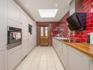 a kitchen with white cabinets and a red brick wall at The Courtyard Apartment - Ukc6965 in Panbride