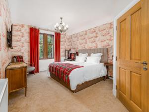 a bedroom with a large bed with red curtains at The Courtyard Apartment - Ukc6965 in Panbride