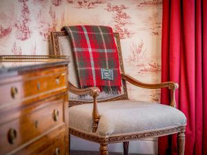 a chair with a plaid blanket sitting next to a dresser at The Courtyard Apartment - Ukc6965 in Panbride