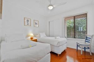 a bedroom with two beds and a chair and a window at Casa Bella in Bongaree